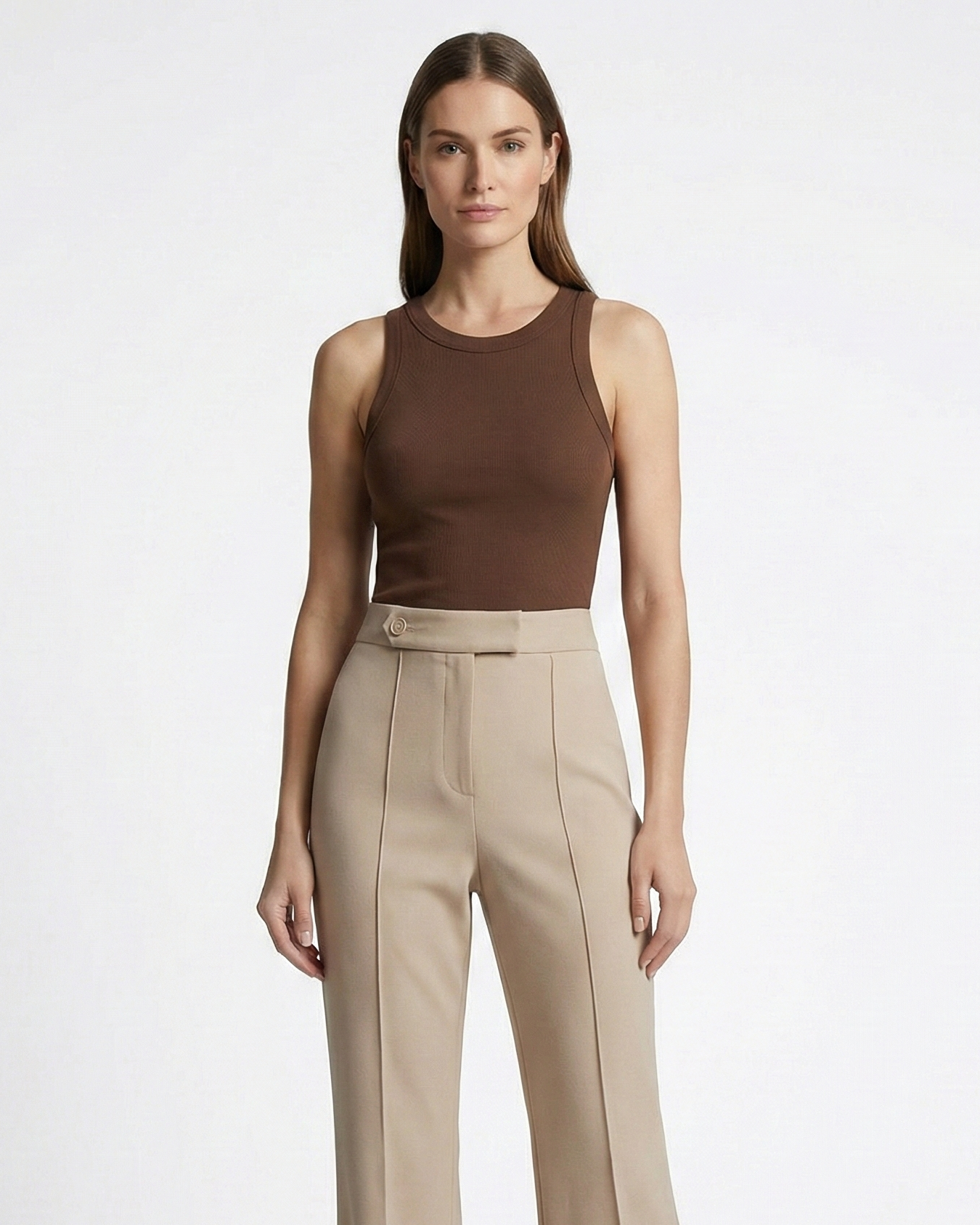 Woman wearing a brown sleeveless top and beige high-waisted pants on a white background