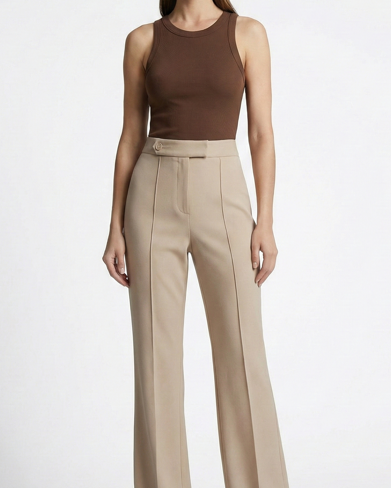 Woman wearing a brown sleeveless top and beige high-waisted pants on a white background