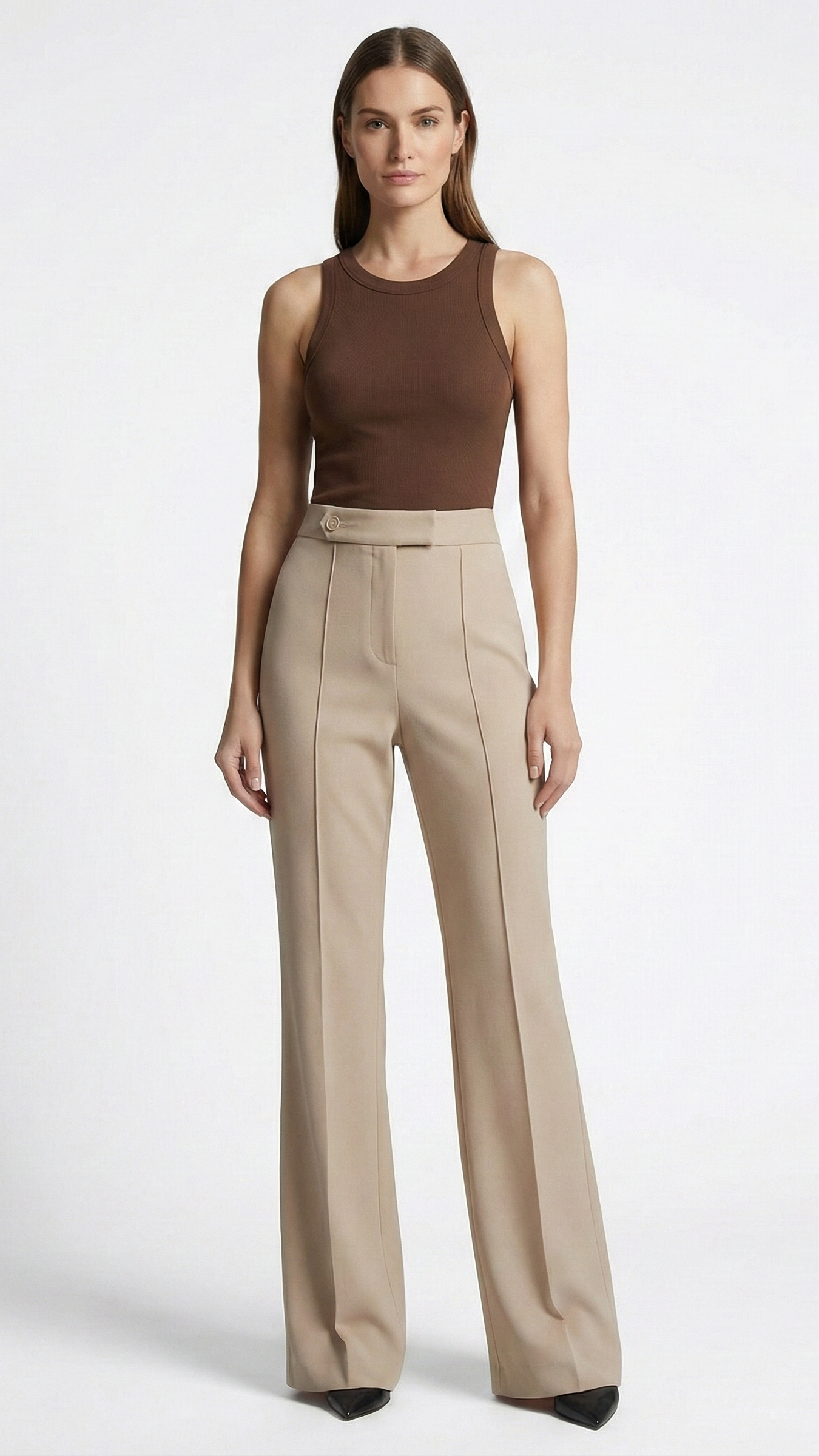Woman wearing a brown sleeveless top and beige high-waisted pants on a white background