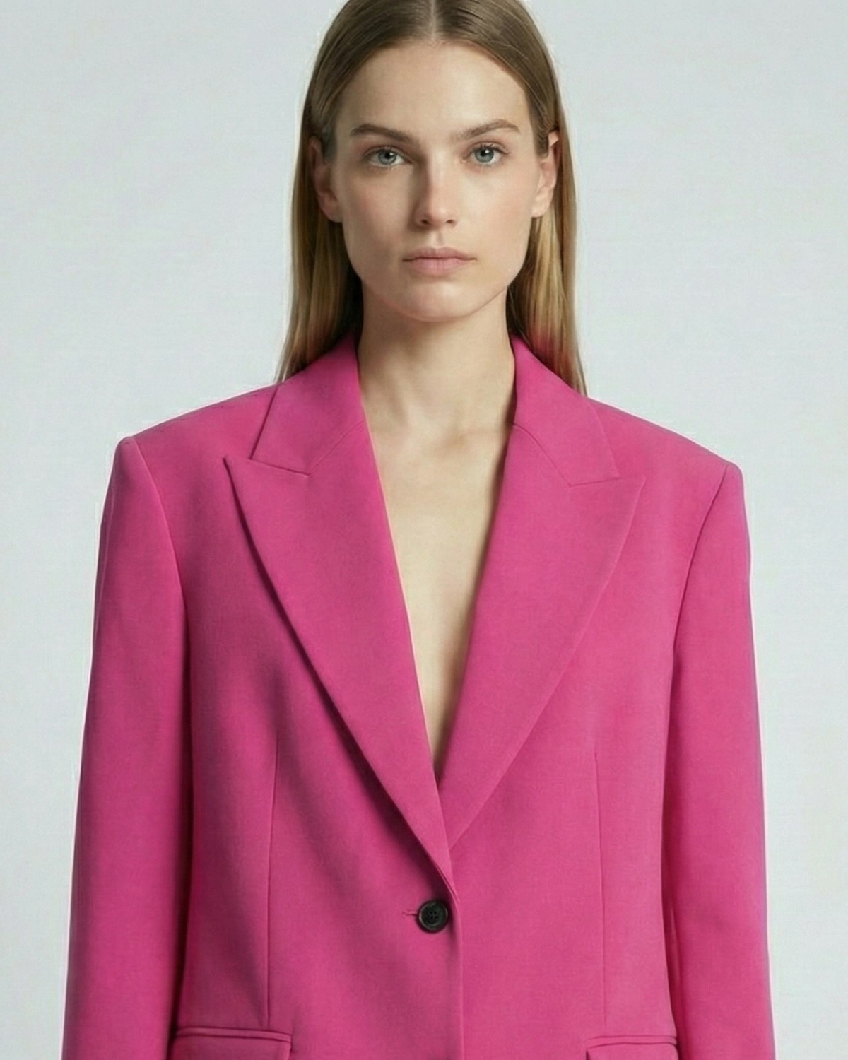 Woman wearing a bright pink suit against a plain background