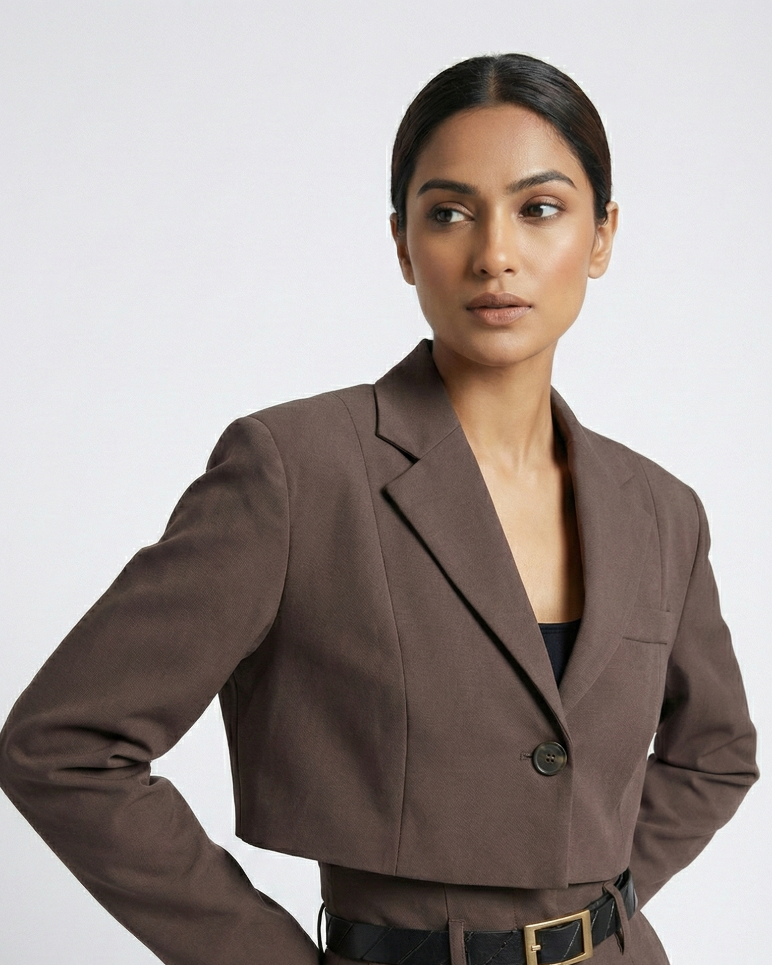 Woman wearing a brown suit with a belt on a white background