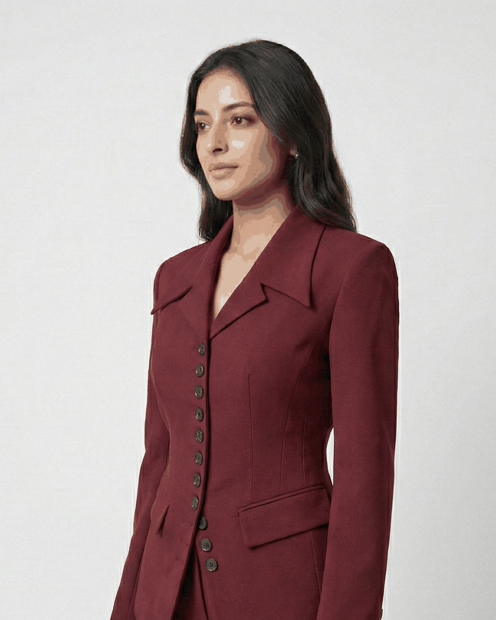 Woman wearing a burgundy suit with a black handbag on a white background