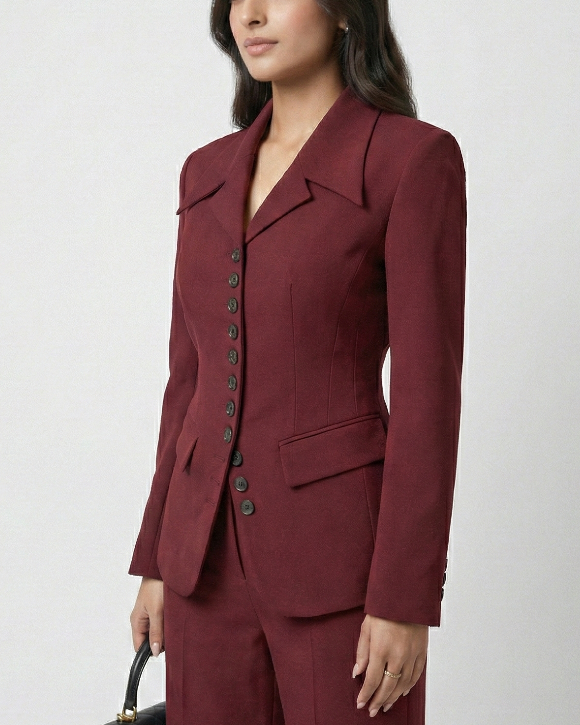 Woman wearing a burgundy suit with a black handbag on a white background