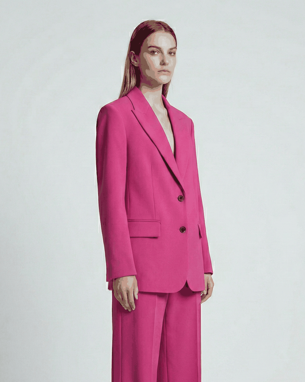Woman wearing a bright pink suit on a white background