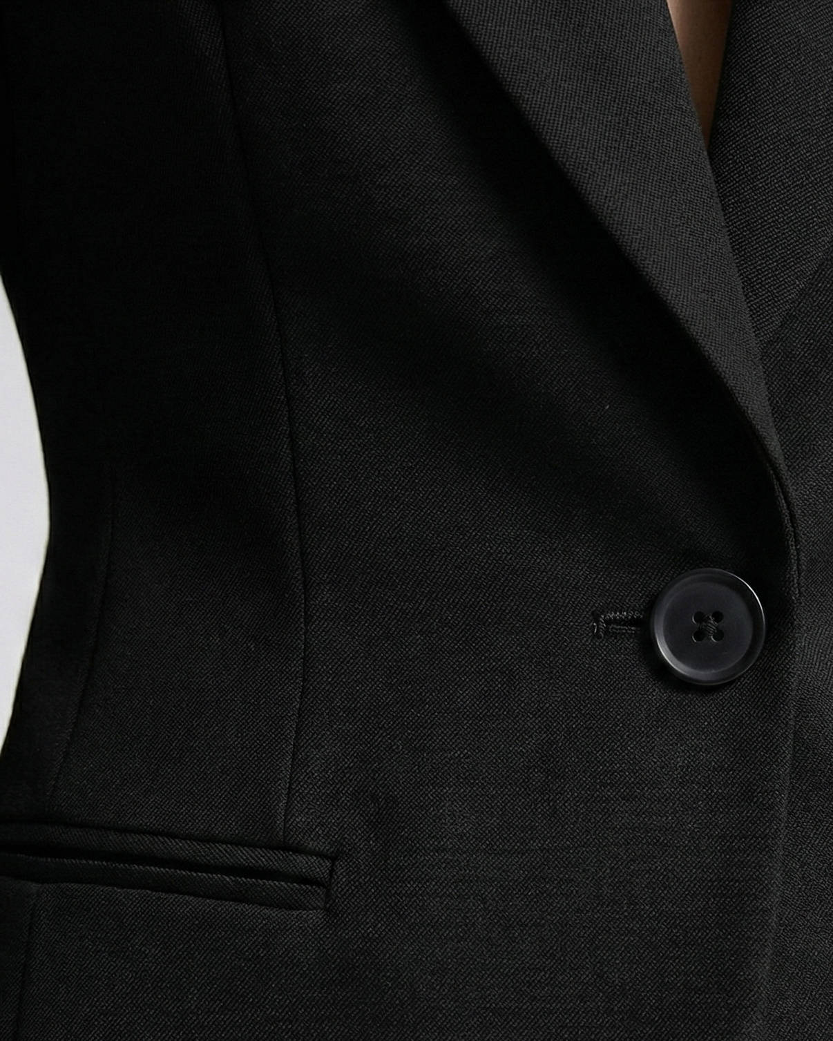 Close-up of a black suit jacket with a button on a white background