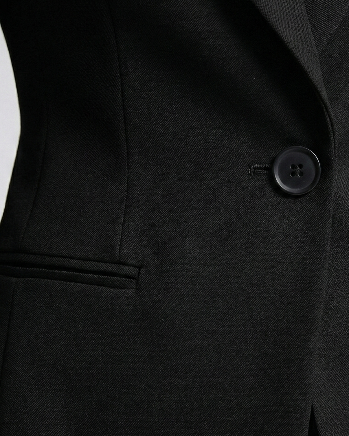 Close-up of a black suit jacket with a button on a white background