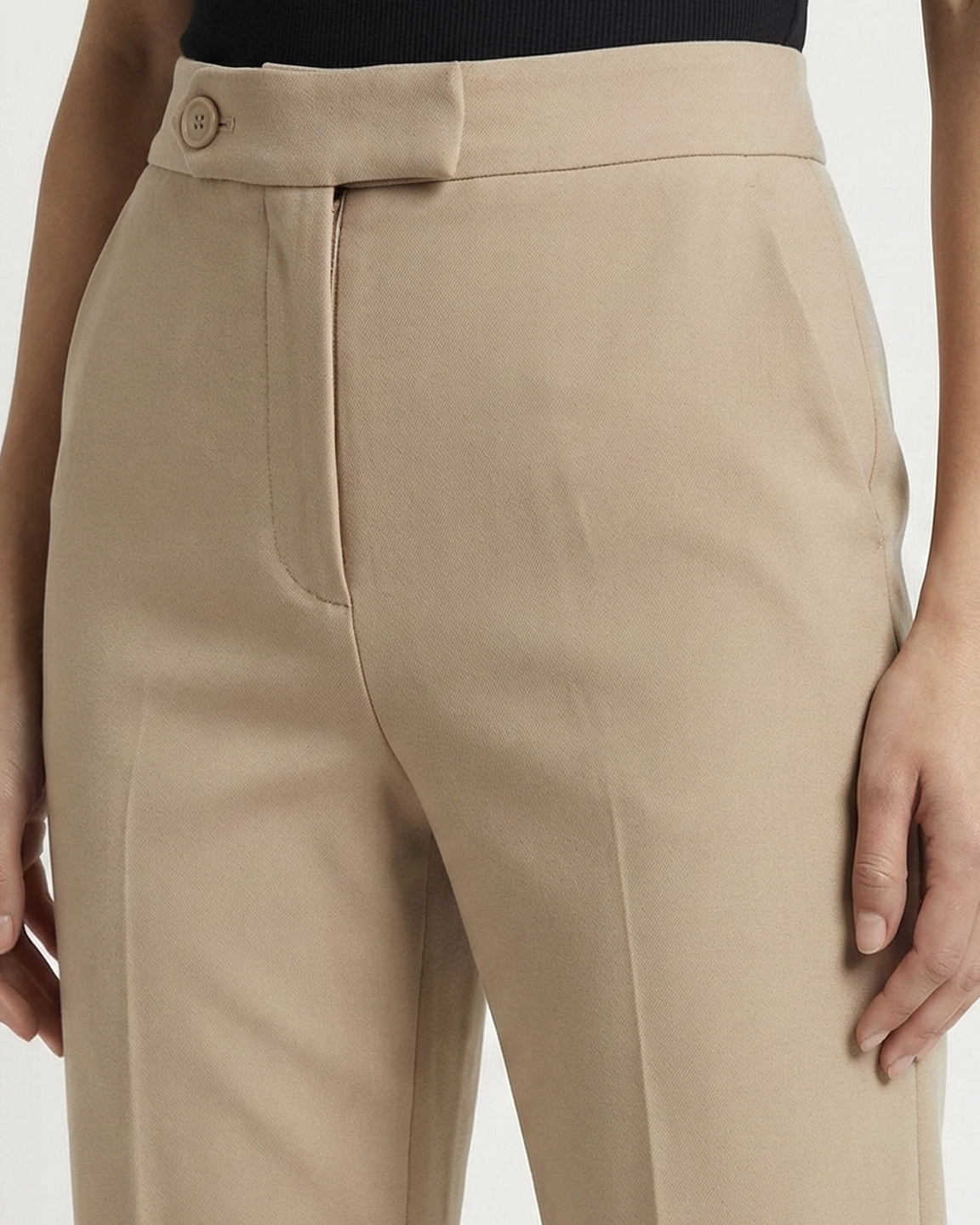 Beige pants worn by a person on a white background