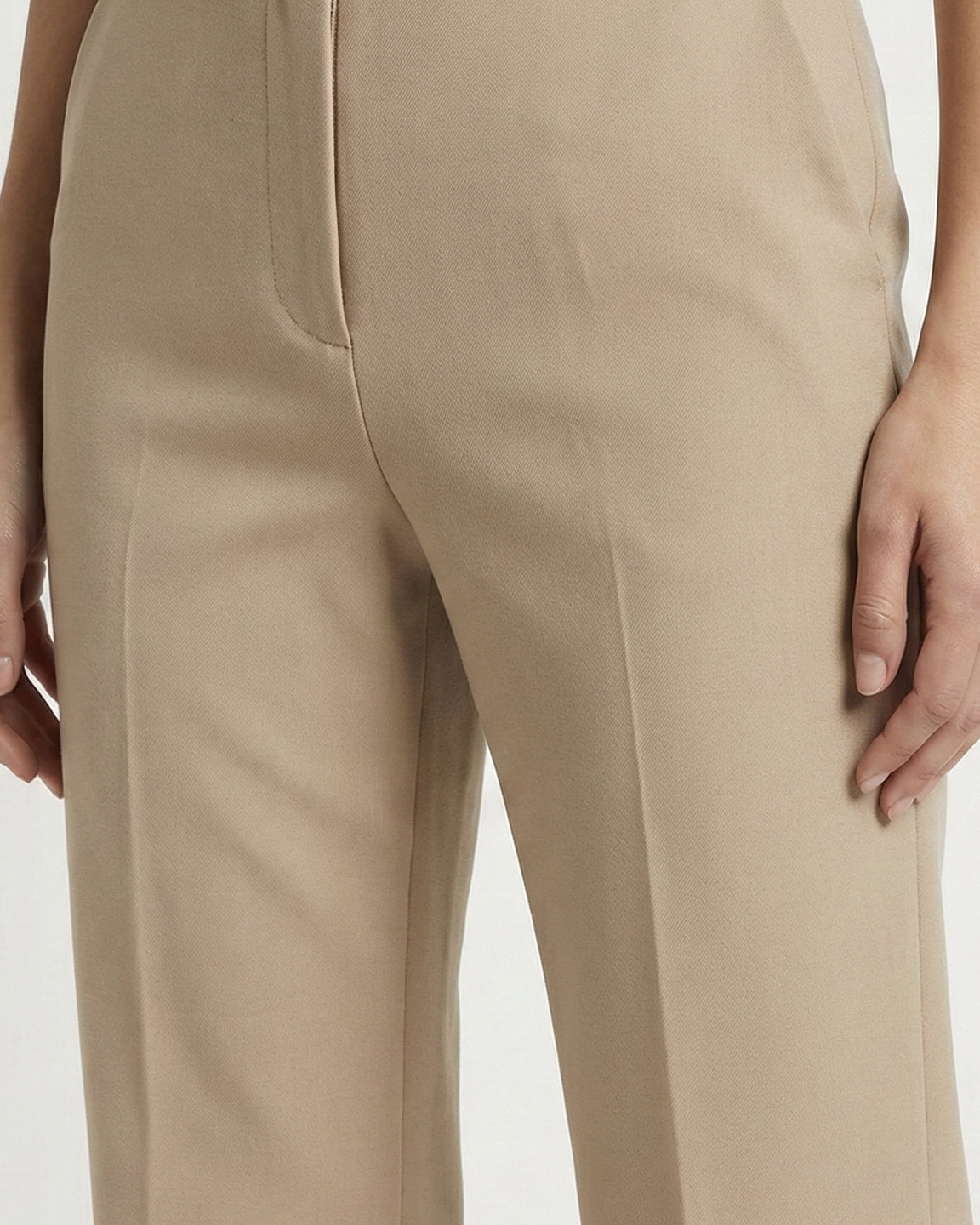Beige pants worn by a person on a white background