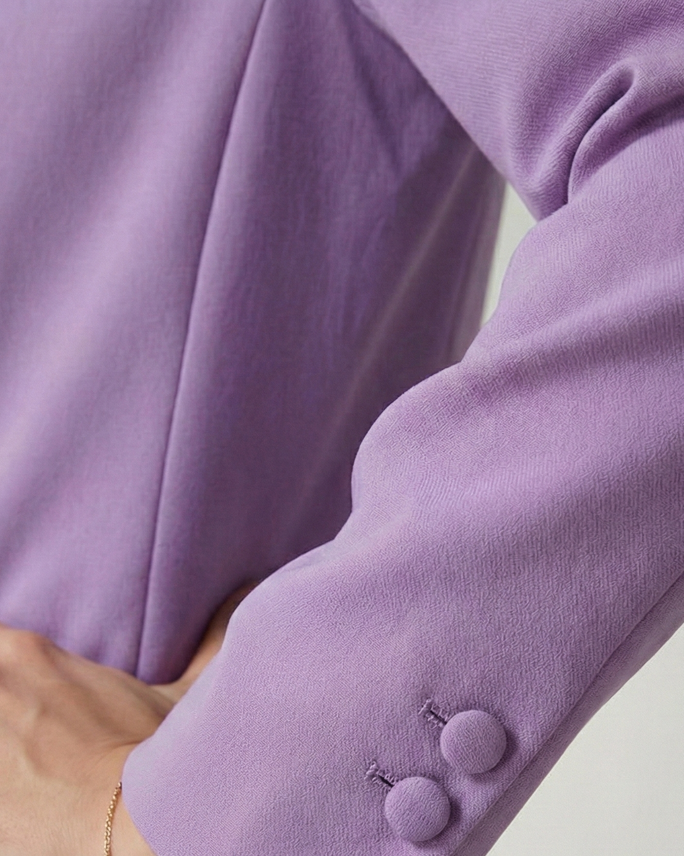 Close-up of a person wearing a light purple suit with a plain background