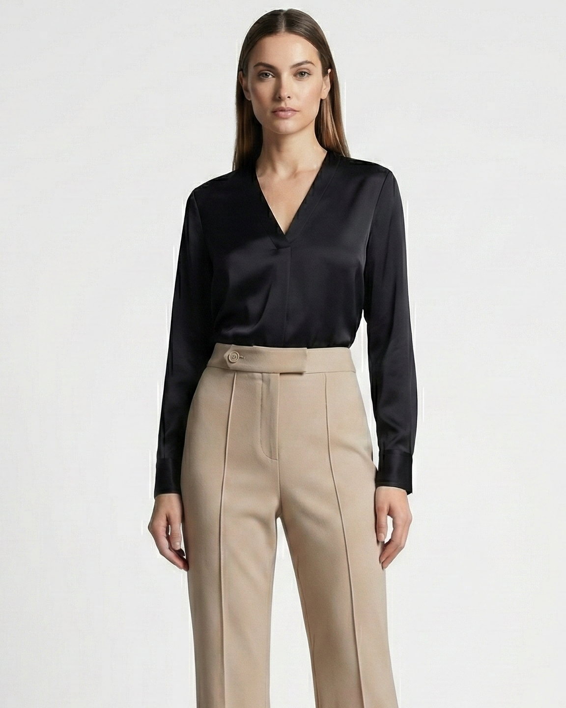 Woman wearing a black blouse and beige pants on a white background