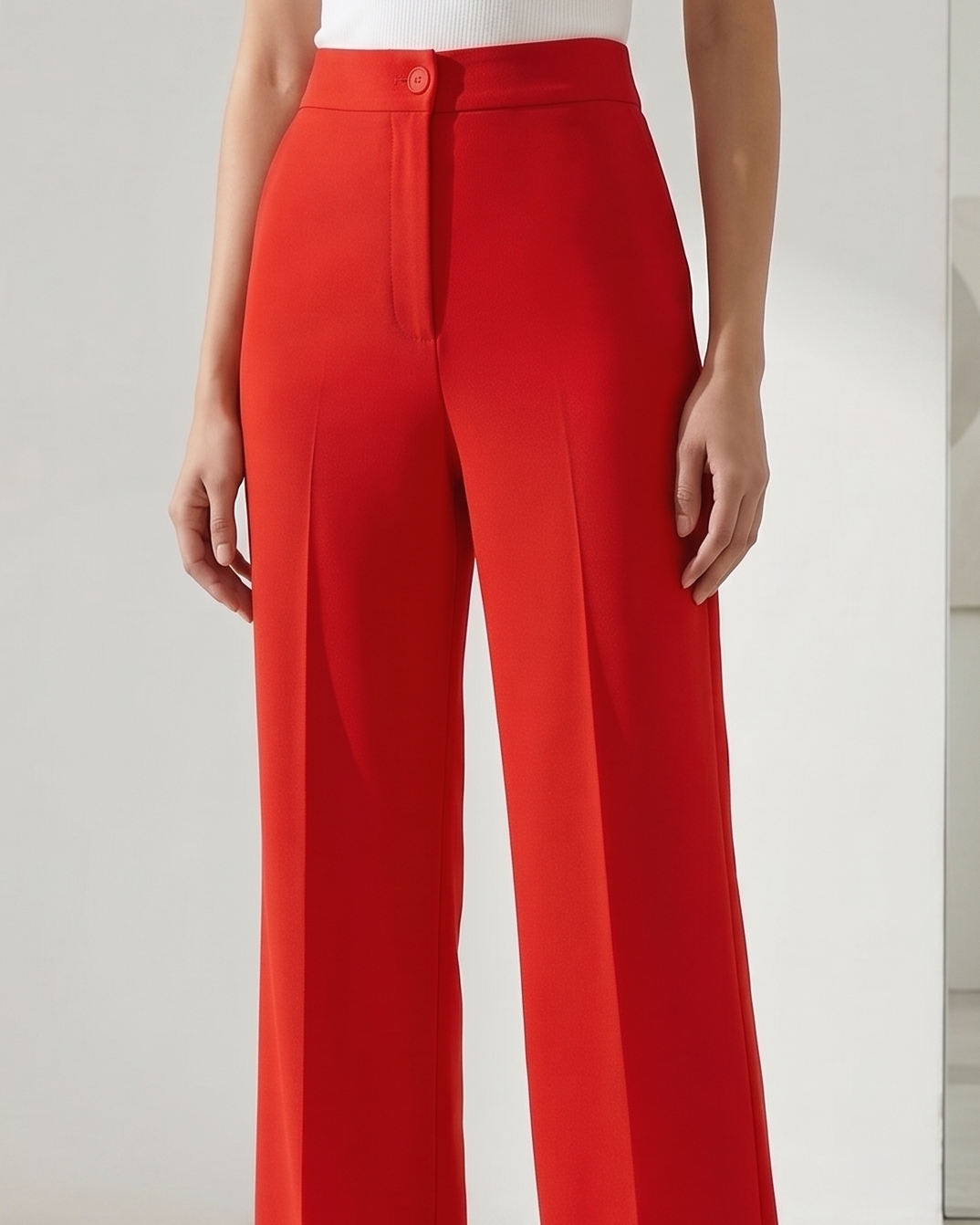 Person wearing a white sleeveless top and red wide-leg pants on a plain background