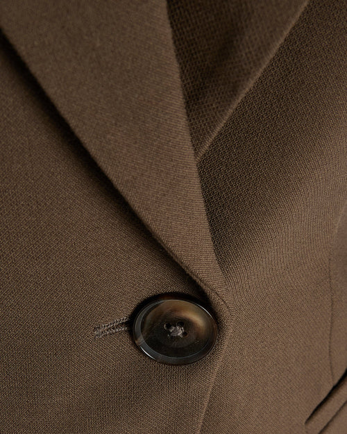 Women's brown fitted blazer with a notched lapel and single closure.