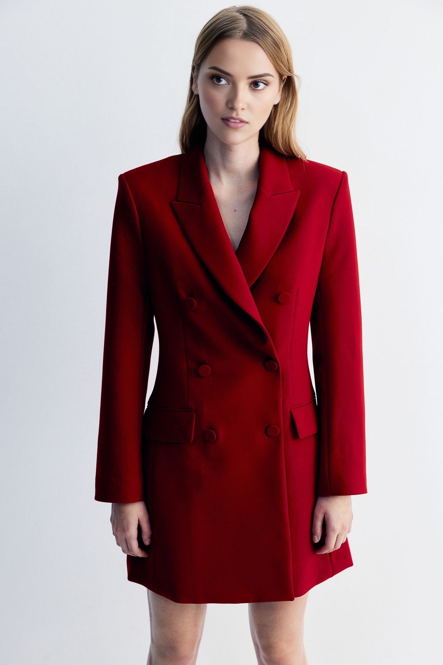 Women's red blazer dress with buttons detailing at waist.