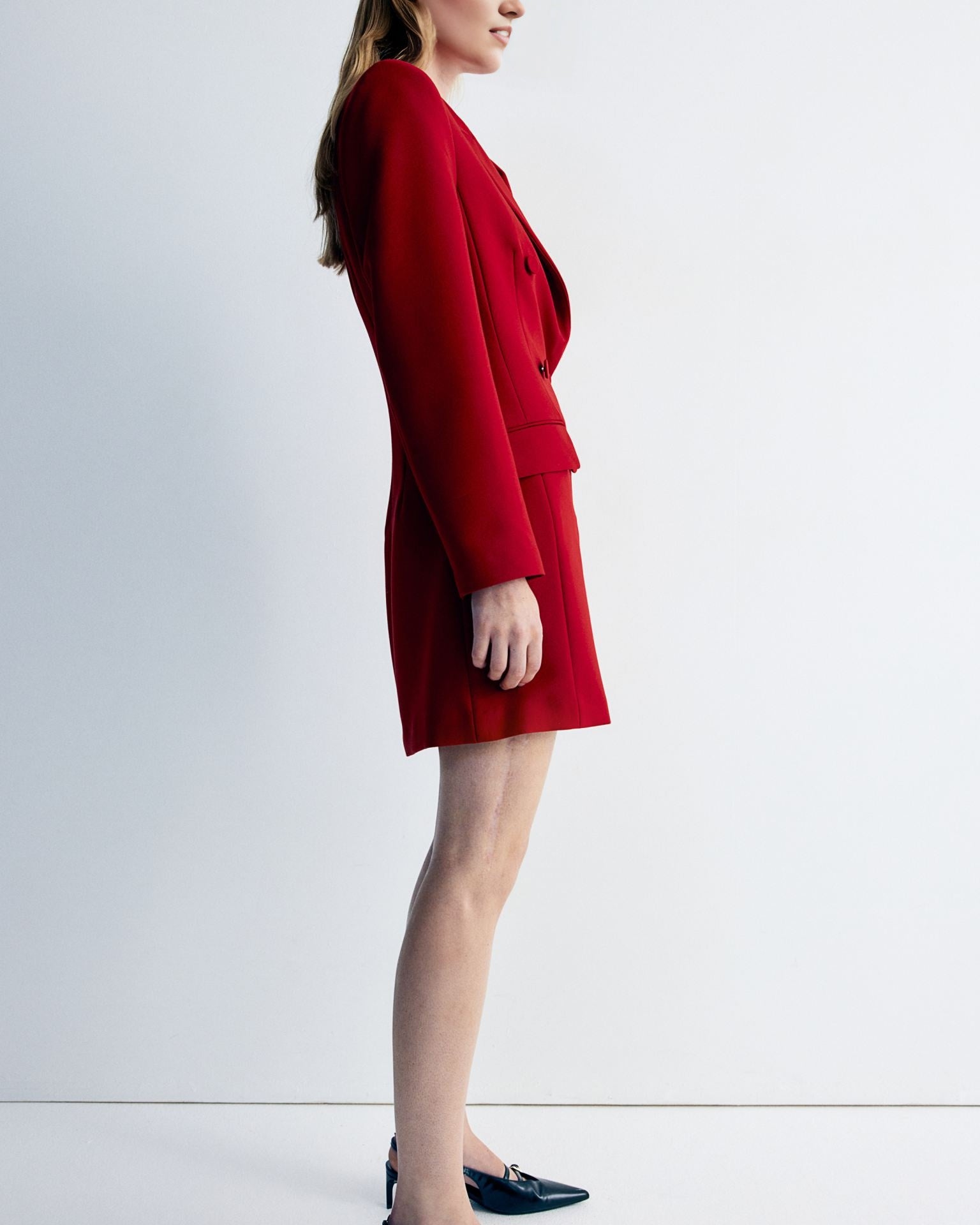 Women's red blazer dress with buttons detailing at waist.
