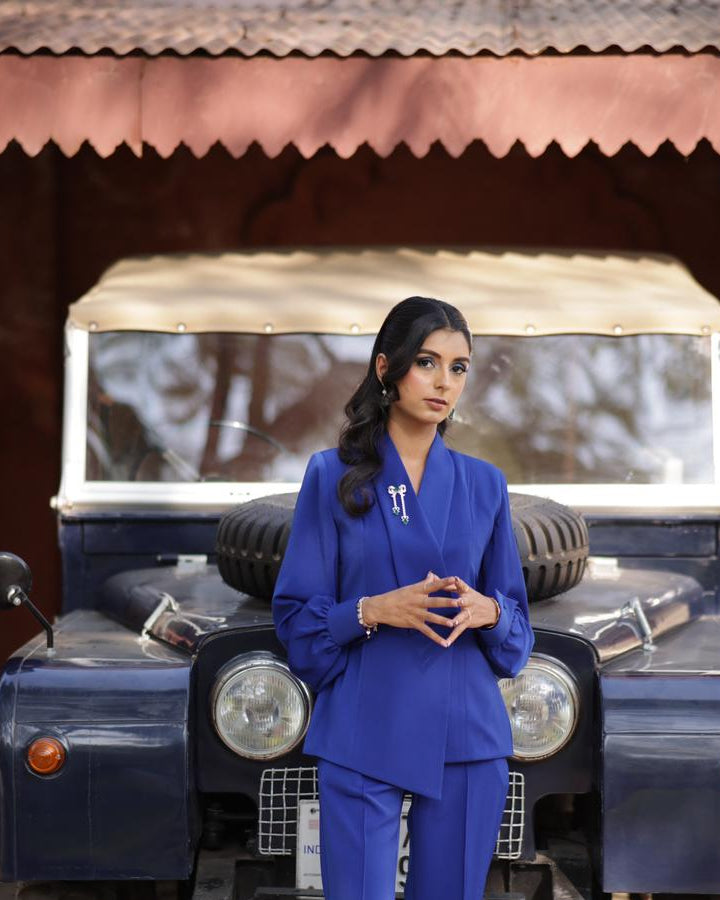 Woman in a blue outfit standing in front of a vintage blue jeep.