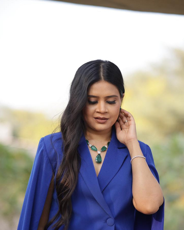 Woman wearing a blue cape with a blurred outdoor background