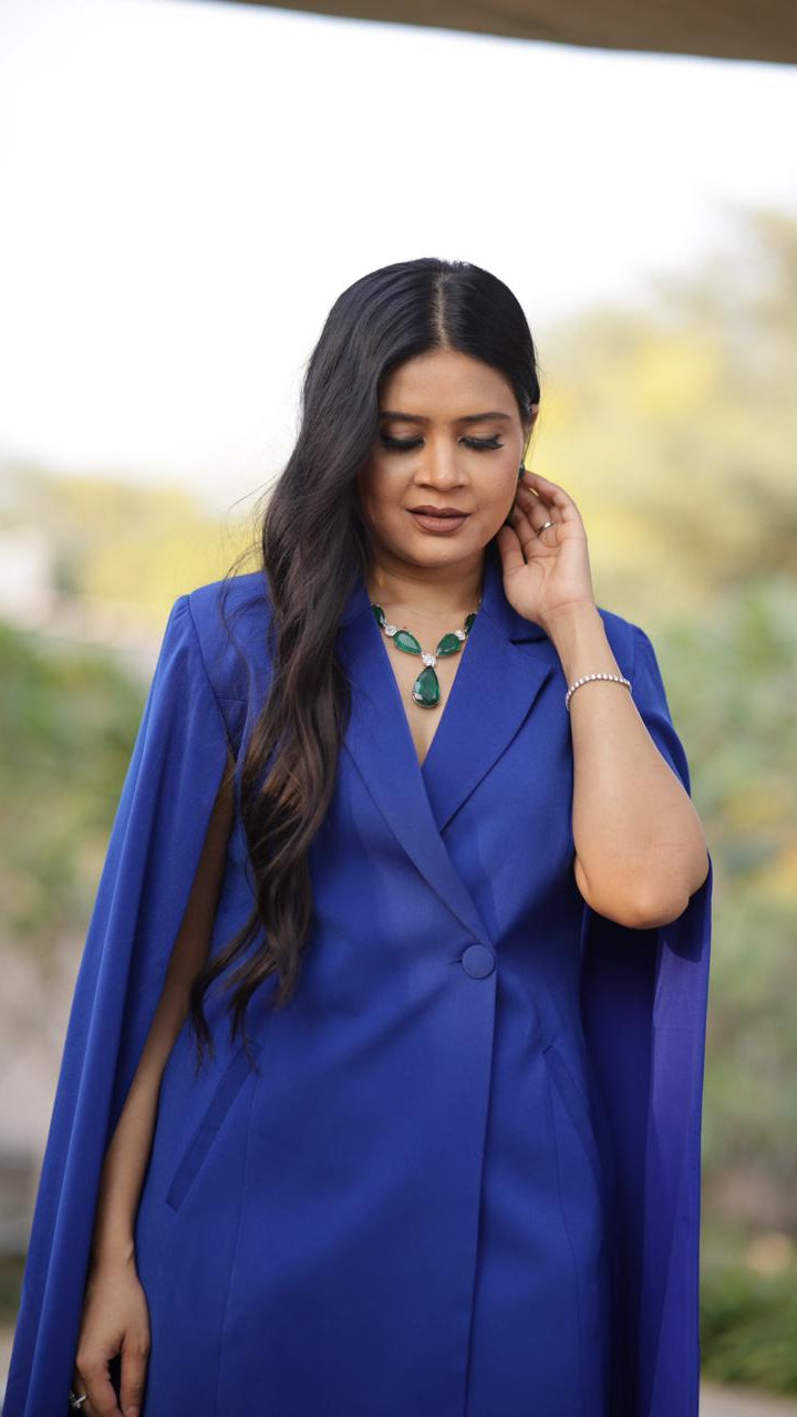 Woman wearing a blue cape with a blurred outdoor background