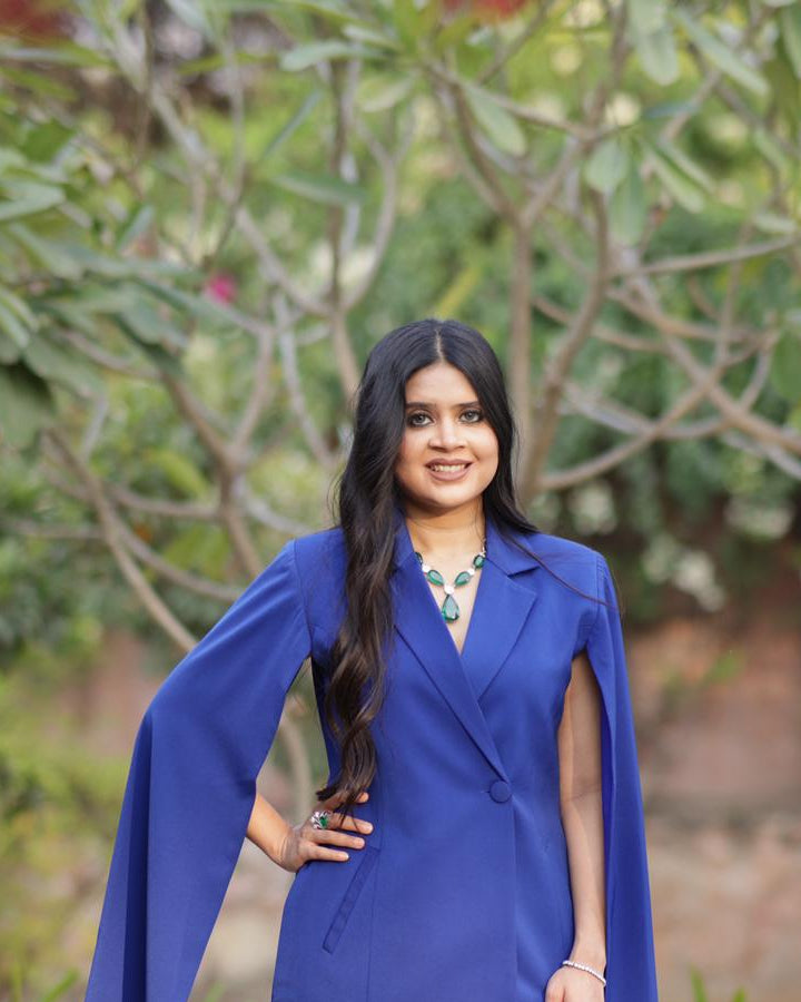 Woman wearing a blue dress with a cape in an outdoor setting