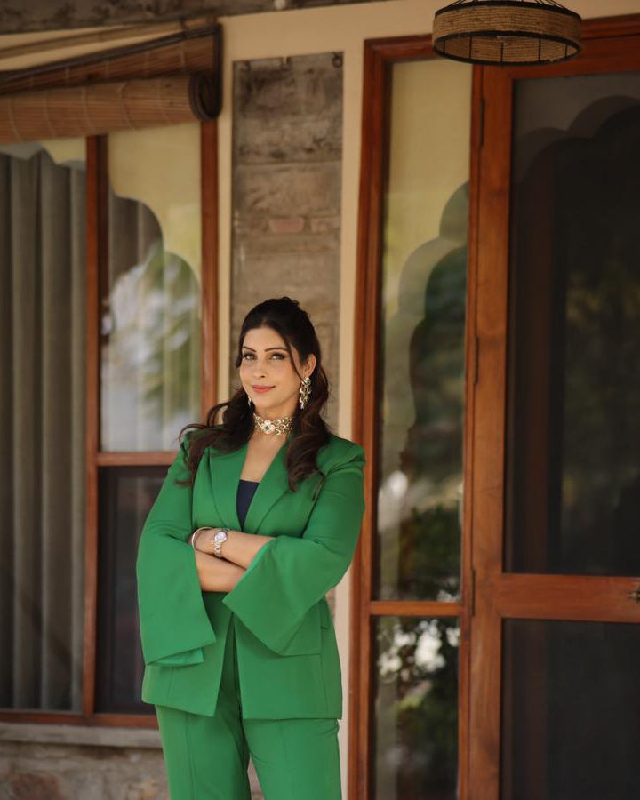 Woman in a green suit standing in front of a wooden door.