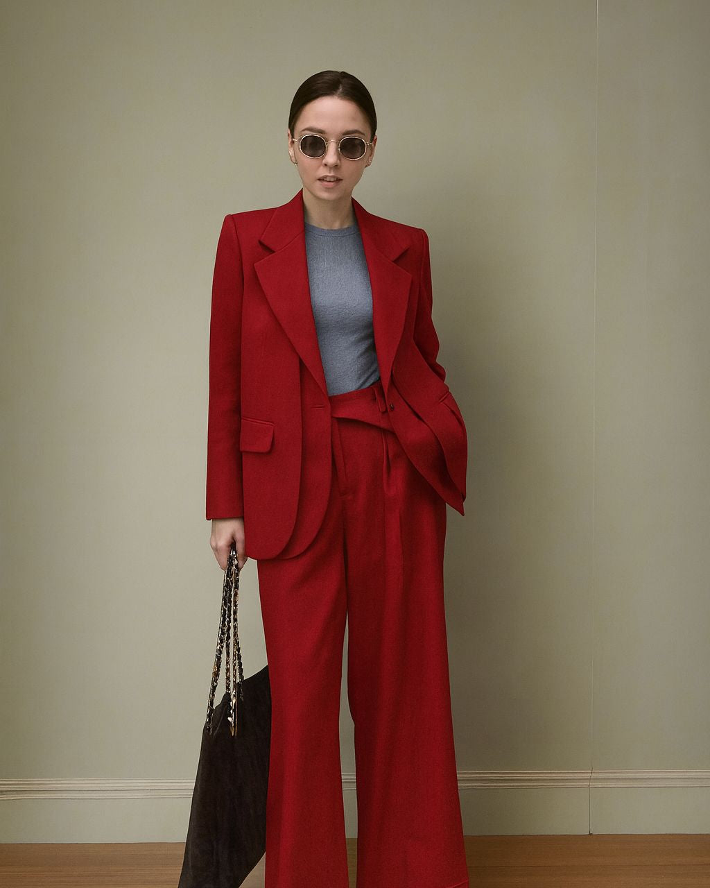 Woman in a red suit standing against a plain background