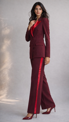 Woman wearing a burgundy suit with red accents on a plain background
