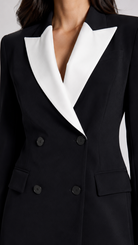Black tuxedo jacket with white lapels on a plain background