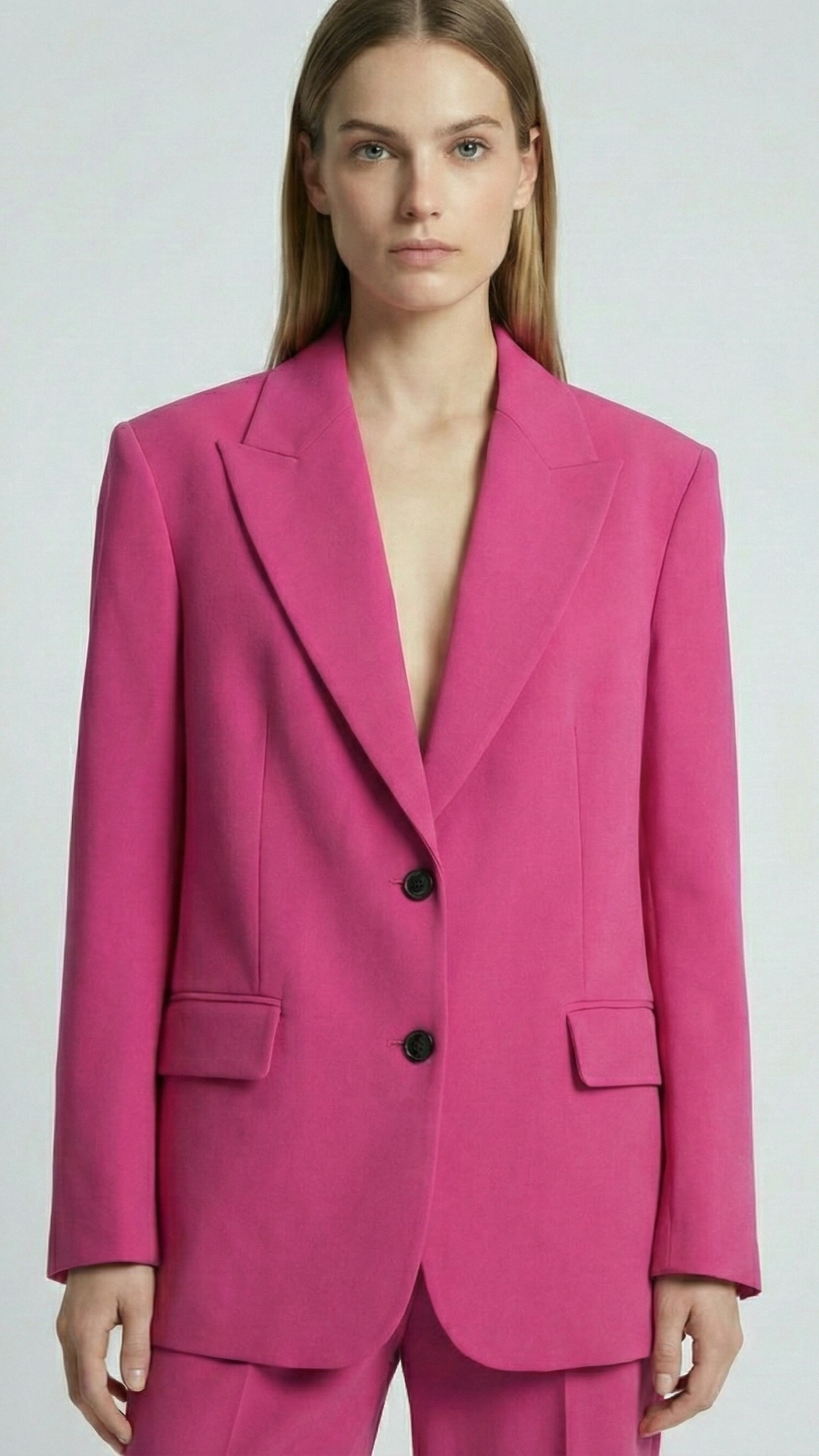 Woman wearing a bright pink suit against a plain background