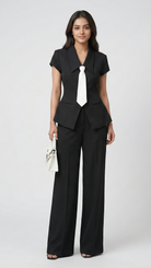 Woman wearing a black suit with a white tie on a white background