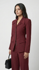 Woman wearing a burgundy suit with a black handbag on a white background
