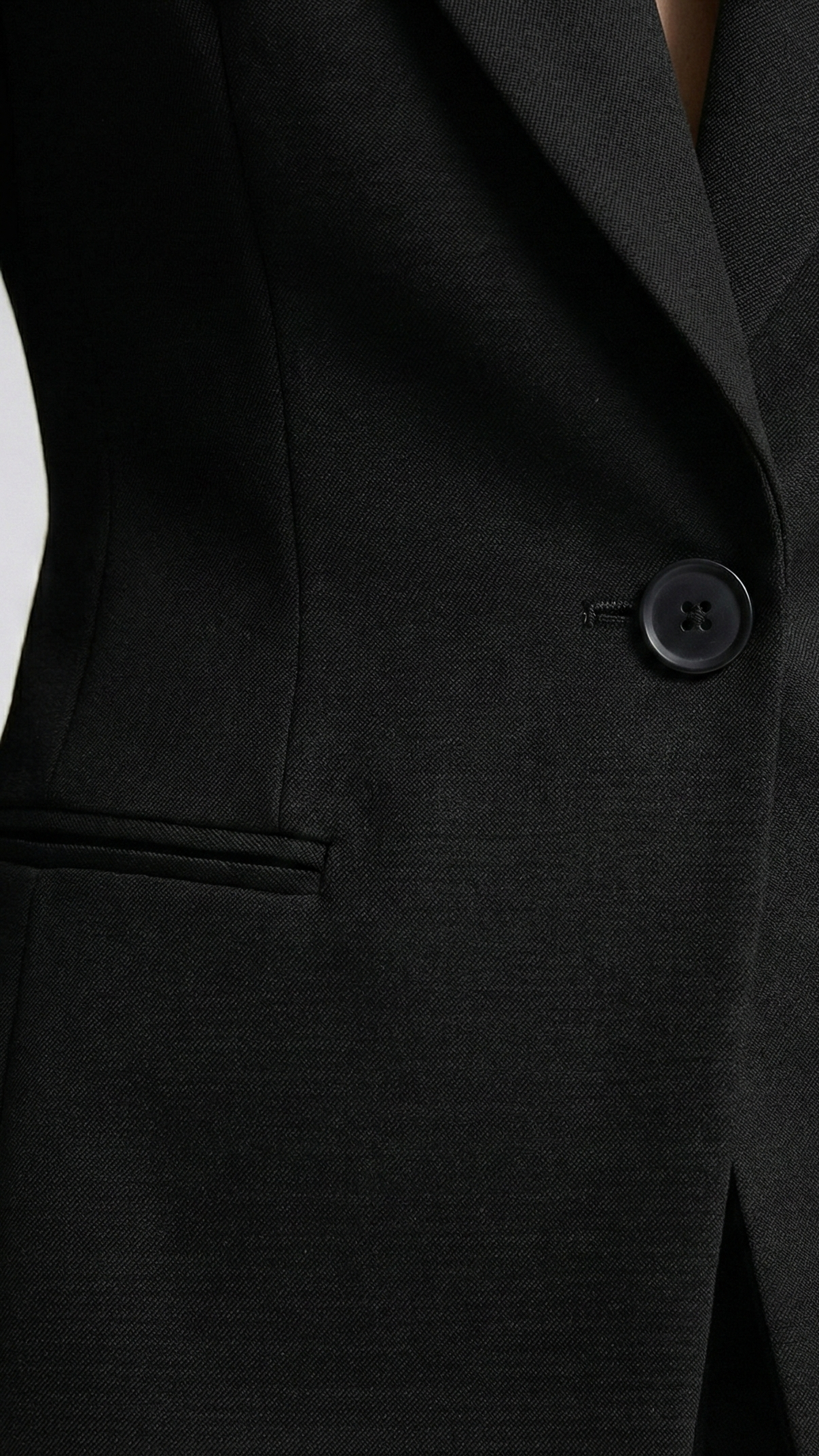 Close-up of a black suit jacket with a button on a white background