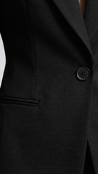 Close-up of a black suit jacket with a button on a white background
