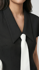 Black dress with a white tie against a plain background