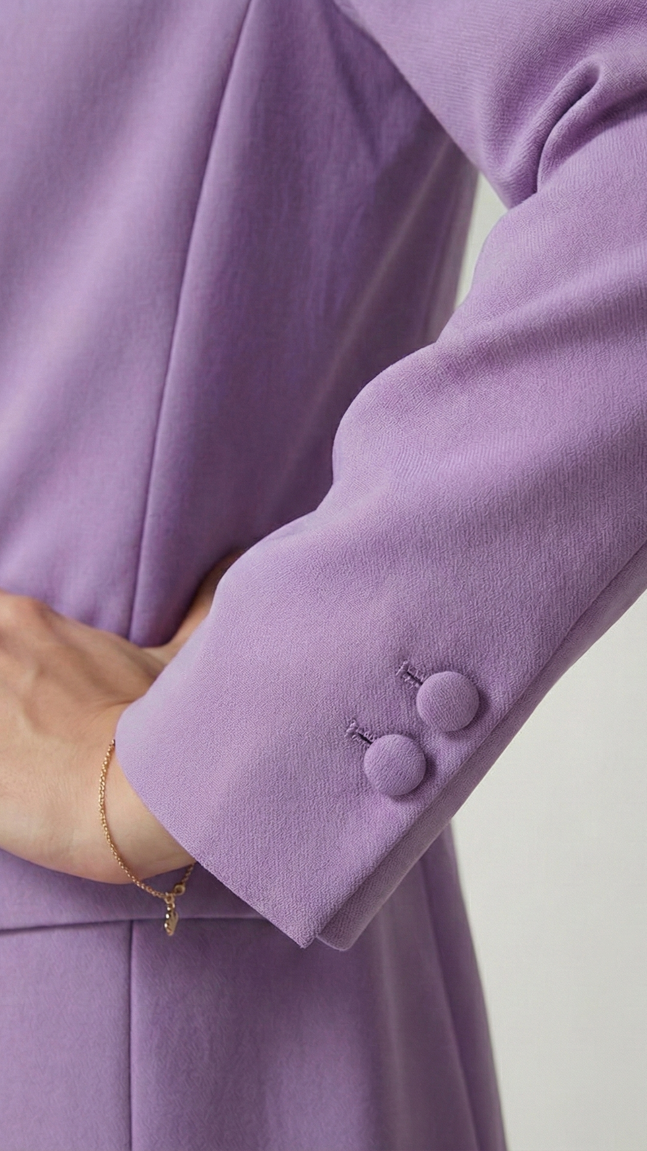 Close-up of a person wearing a light purple suit with a plain background