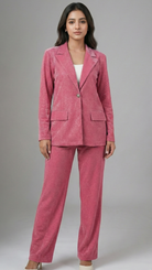 Woman wearing a pink suit standing against a gray background
