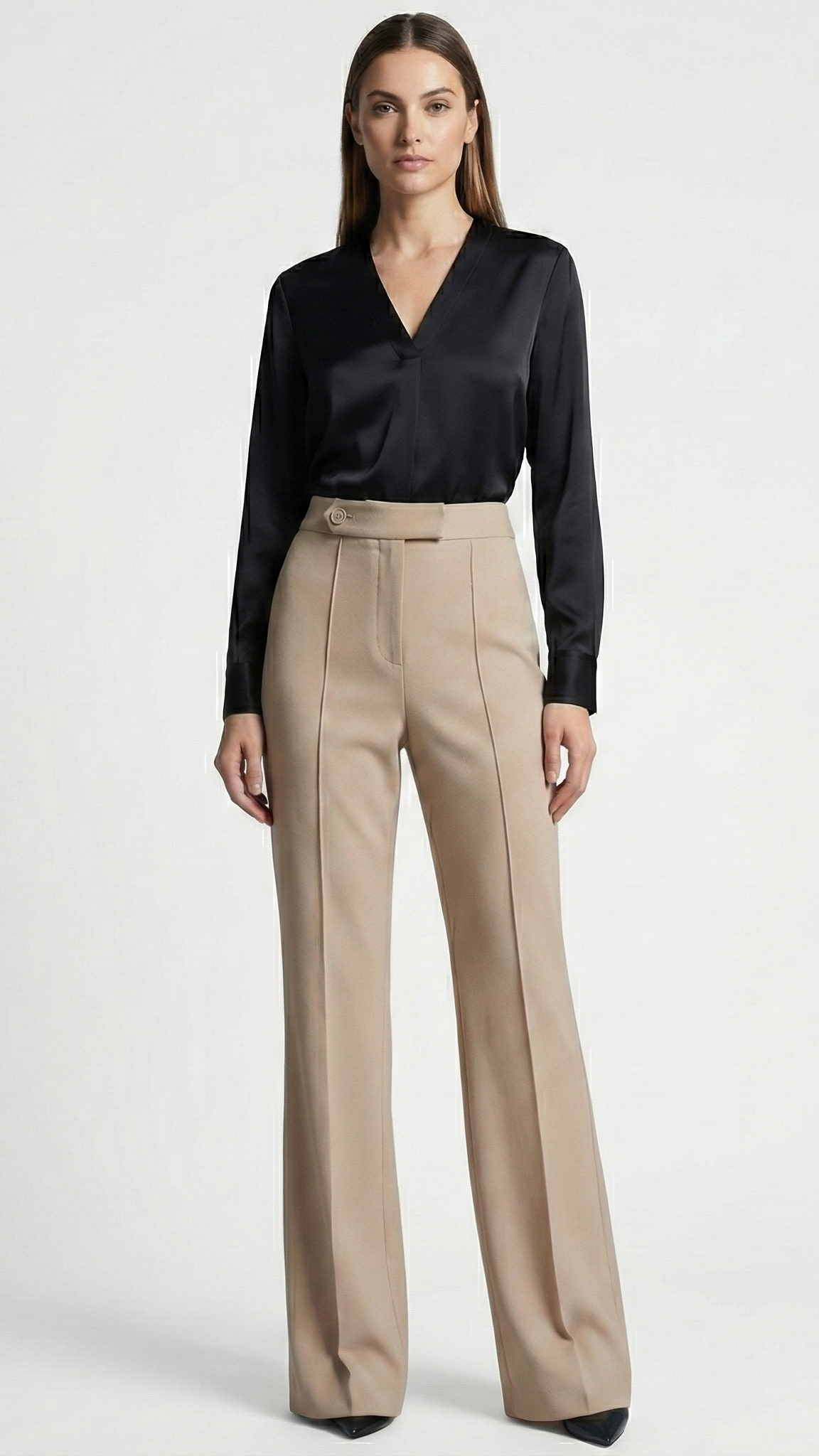Woman wearing a black blouse and beige pants on a white background