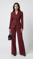 Woman wearing a burgundy suit holding a black handbag on a white background