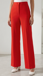 Person wearing a white sleeveless top and red wide-leg pants on a plain background