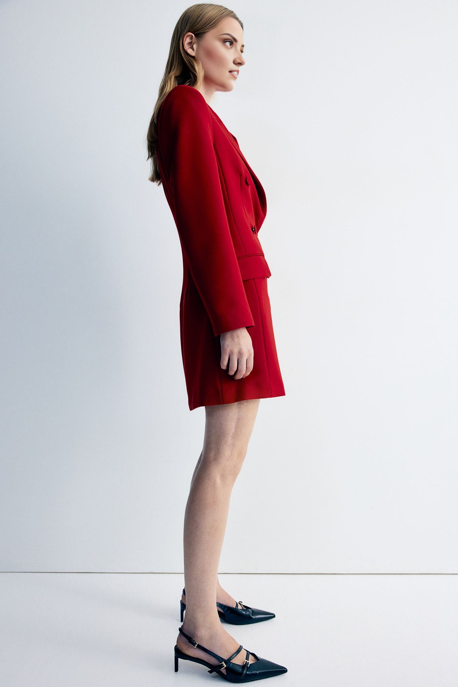 Women's red blazer dress with buttons detailing at waist.