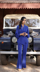Woman in a blue outfit standing in front of a vintage blue jeep.