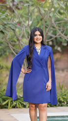 Woman wearing a blue dress with a cape in an outdoor setting