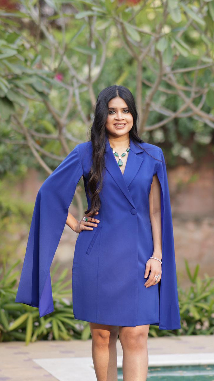Woman wearing a blue dress with a cape in an outdoor setting