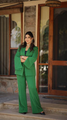 Woman in a green suit standing in front of a wooden door.