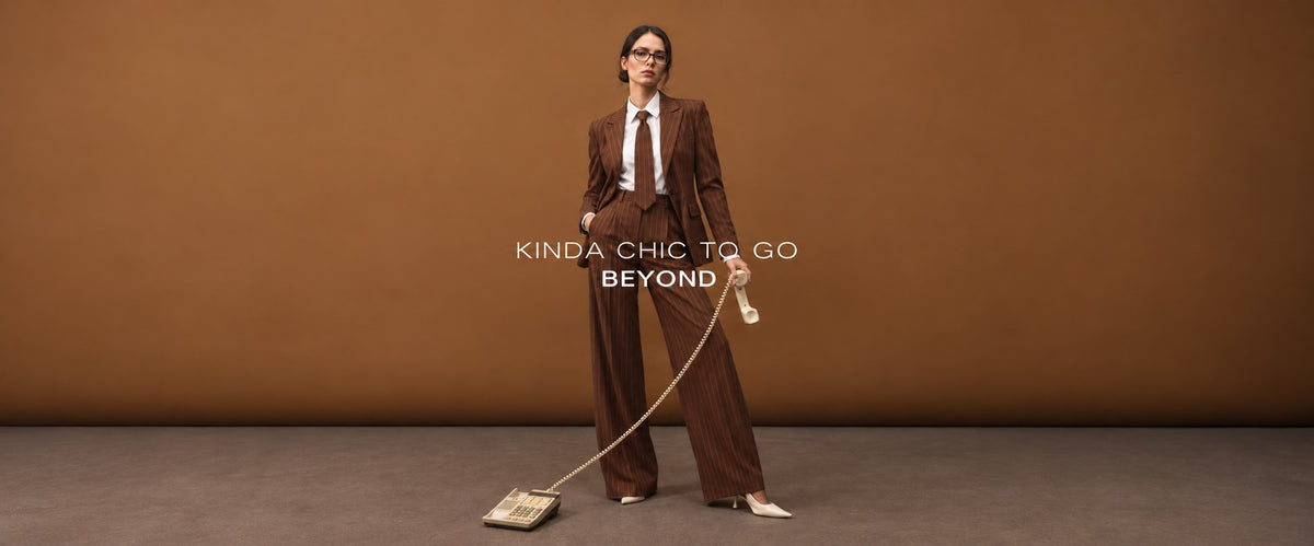Woman in a brown pinstripe pant suit with tie holding a vintage phone – Kinda chic to go Beyond | Beyond Formals