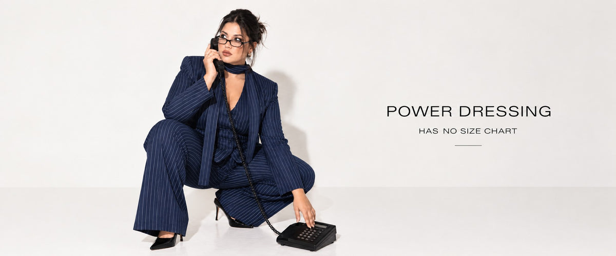 Woman in a navy pinstripe pant suit crouching with a telephone – Power dressing has no size chart | Beyond Formals